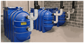 Grease arrestor operation diagram: wastewater enters the inlet, internal pipework feeds the tank base, sludge settles, grease floats to the surface and treated water discharges to sewer